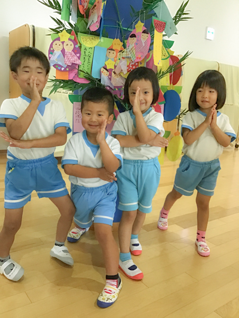 七夕飾りの前でポーズをとる子どもたち