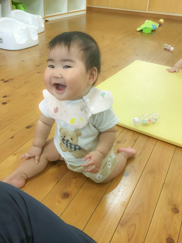 床に座って笑う赤ちゃん