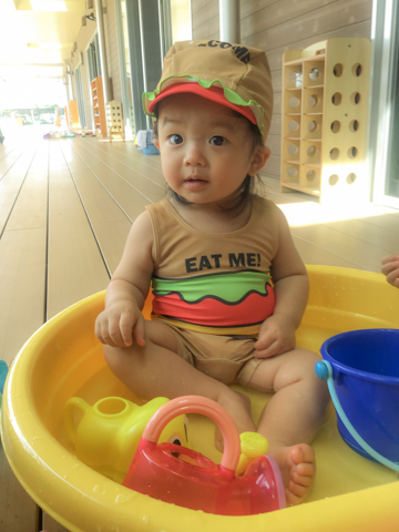 たらいの中で水遊びをする子ども