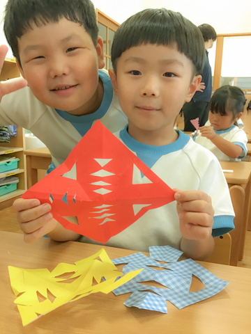 切り紙の作品を見せる子どもたち